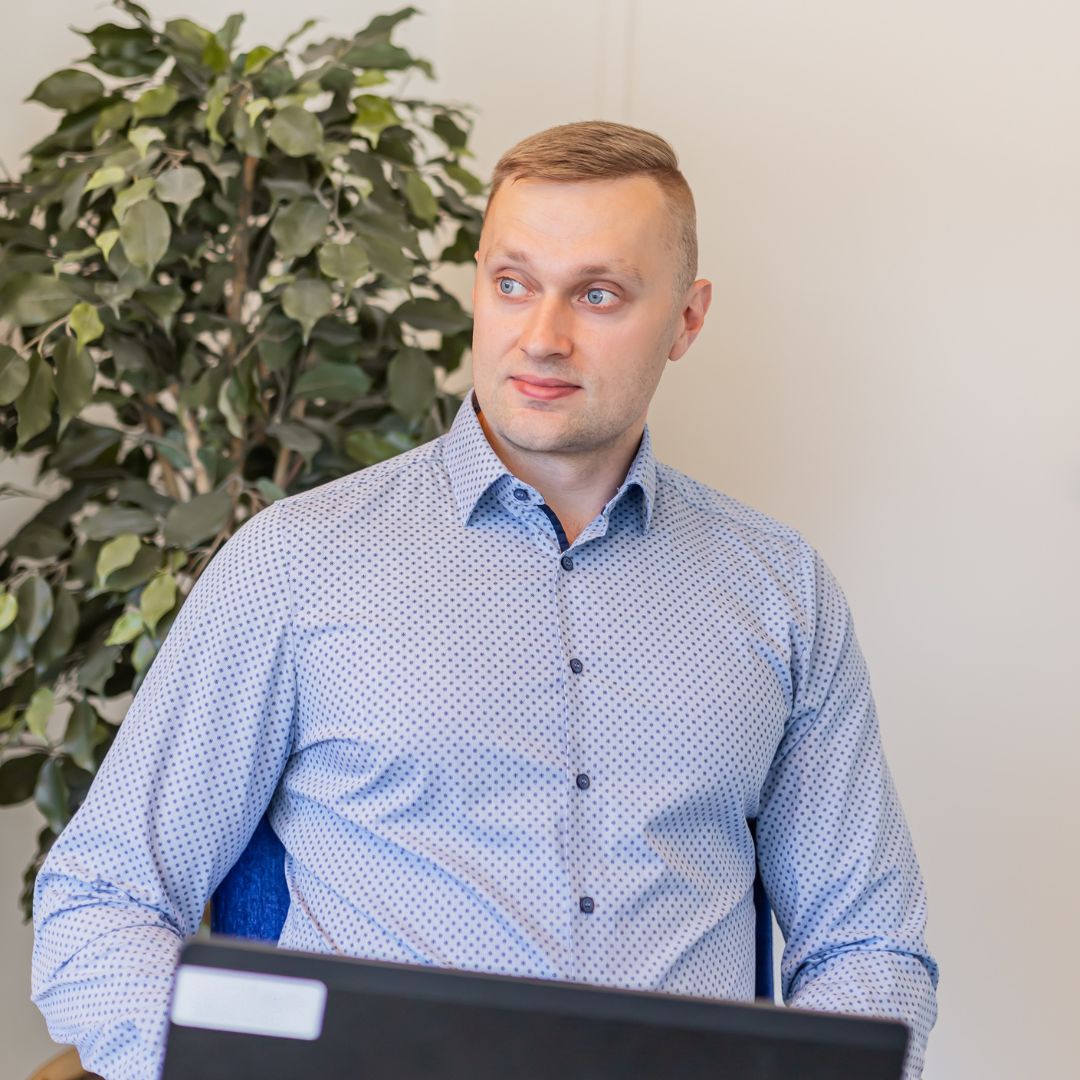 henkilö sinisessä paidassa ja viherkasvi taustalla